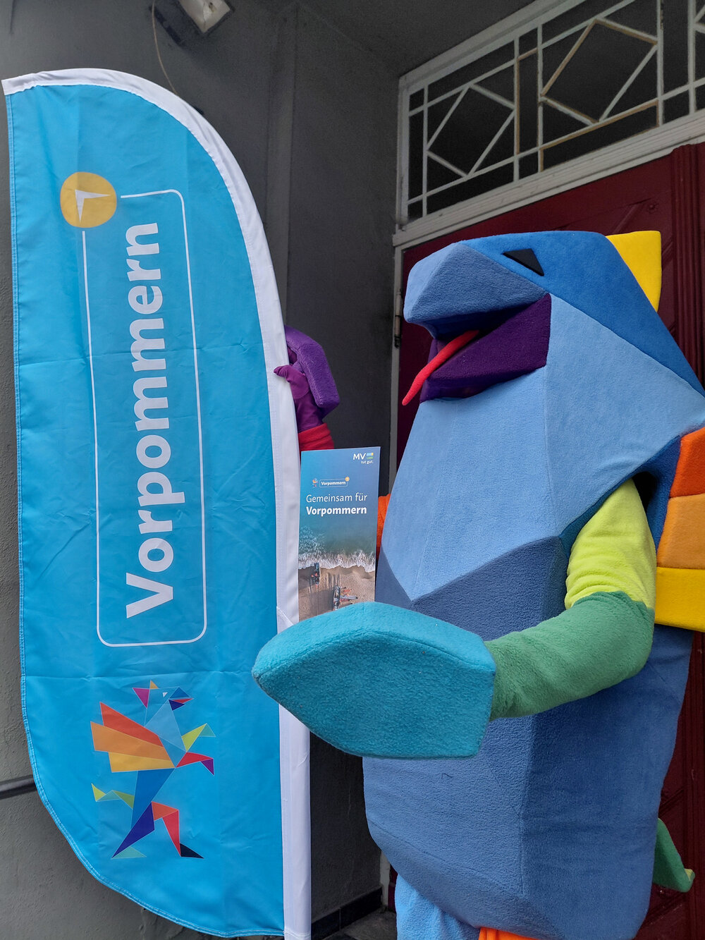 Vorpommern-Maskottchen mit Beach-Flag und Flyer